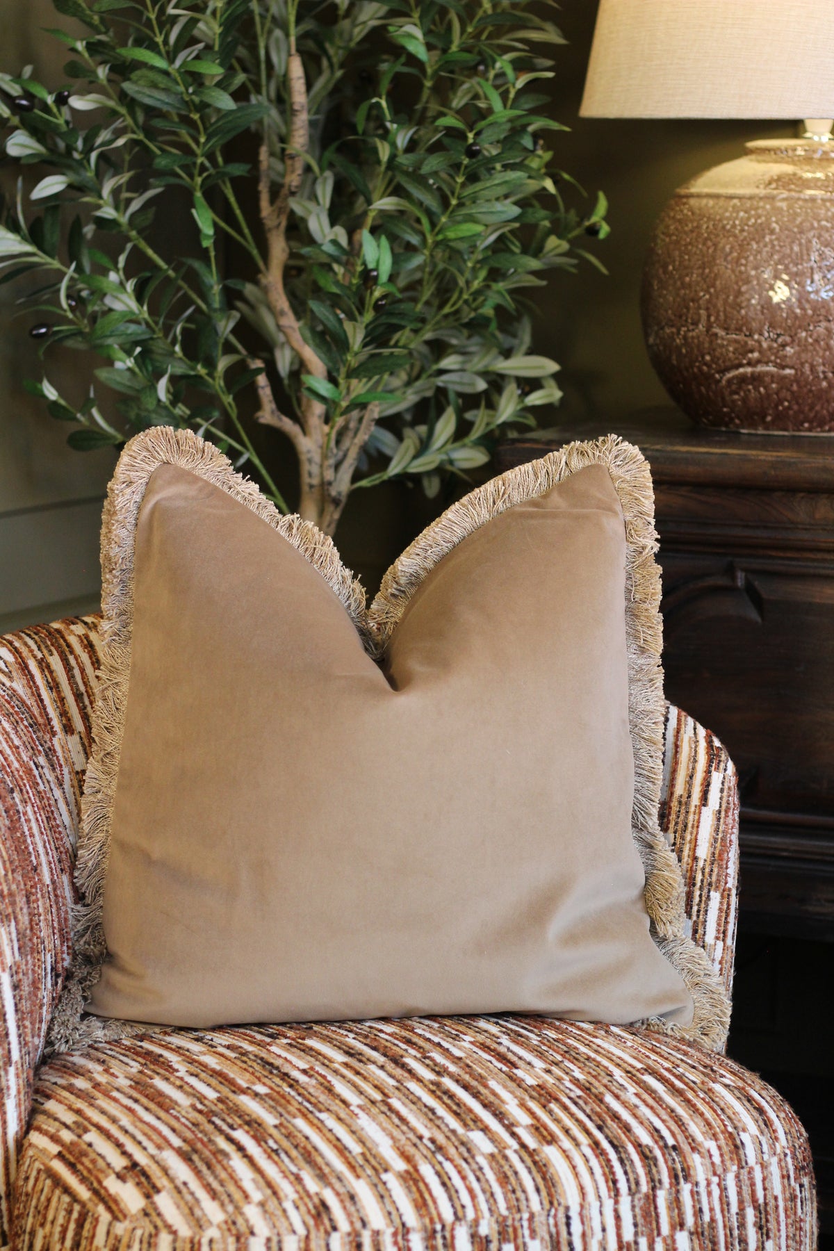 Langford Stone fringed velvet cushion in a warm neutral tone, 55 x 55cm