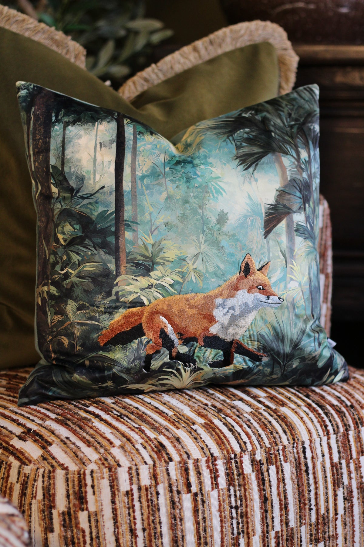 Bracken forest print cushion with embroidered fox styled on a brown striped chair