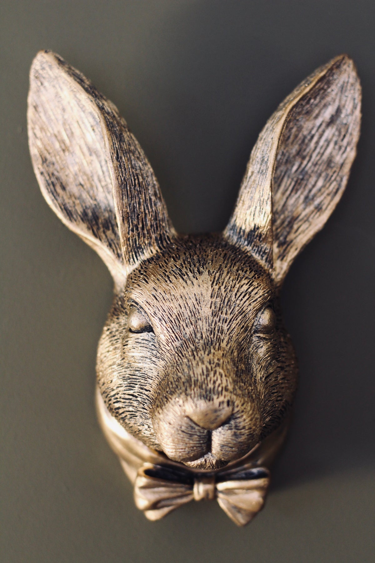 Close-up of the detailed antique gold rabbit face and bow tie